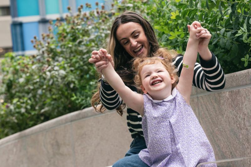 A woman holding a young girl's hands up above her head